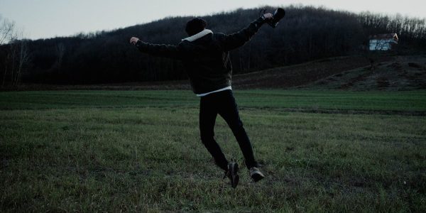A person joyfully jumps in a serene open field at twilight, capturing a sense of freedom and adventure.